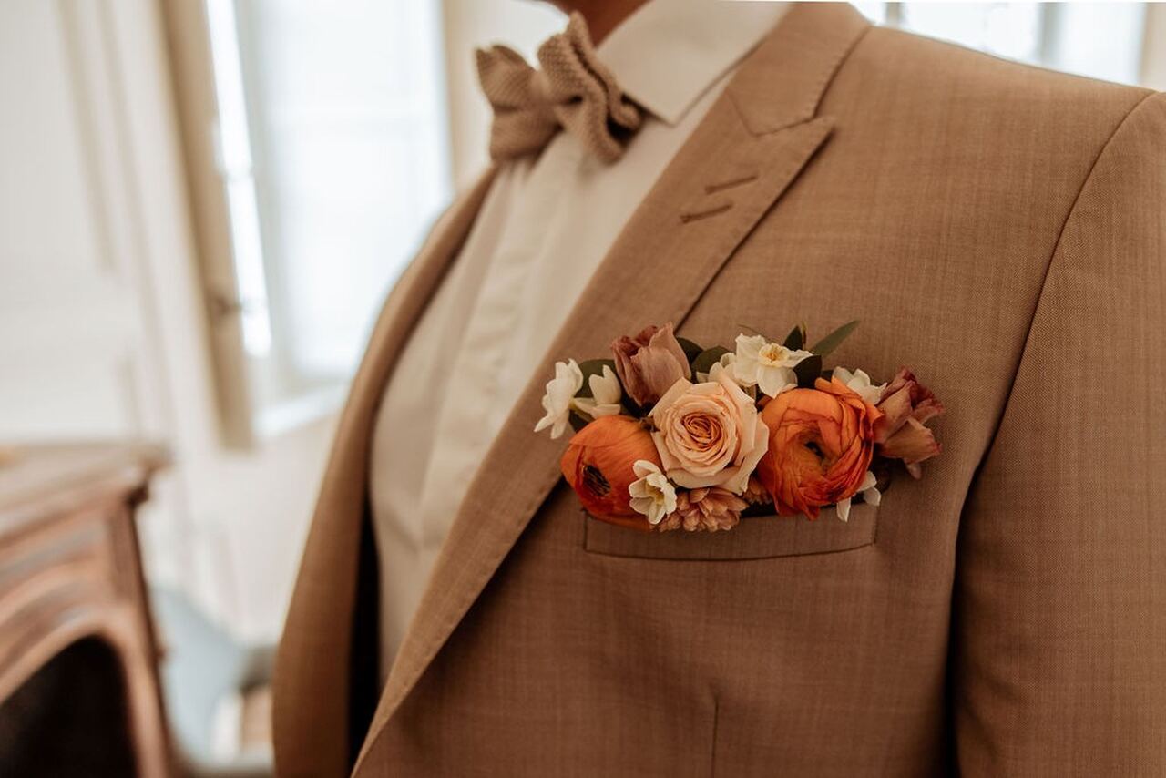 Bolso do terno bege do noivo cheio de flores em cor pêssego