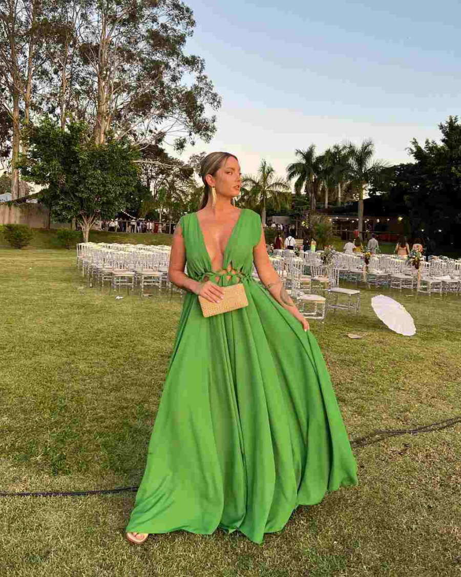 Mulher de vestido verde com uma bolsa de mão nude