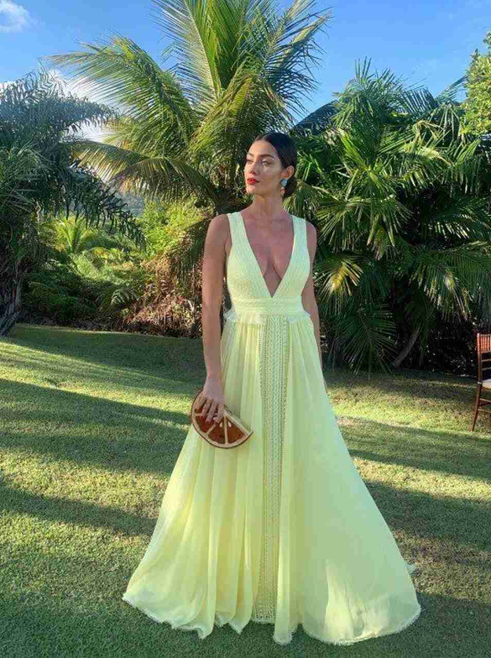 Mulher de vestido em tom pastel e bolsa de mão em formato de limão cortado