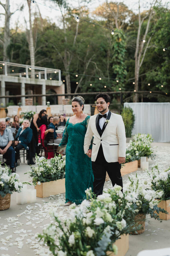 entrada do noivo com smoking branco e mãe com vestido verde