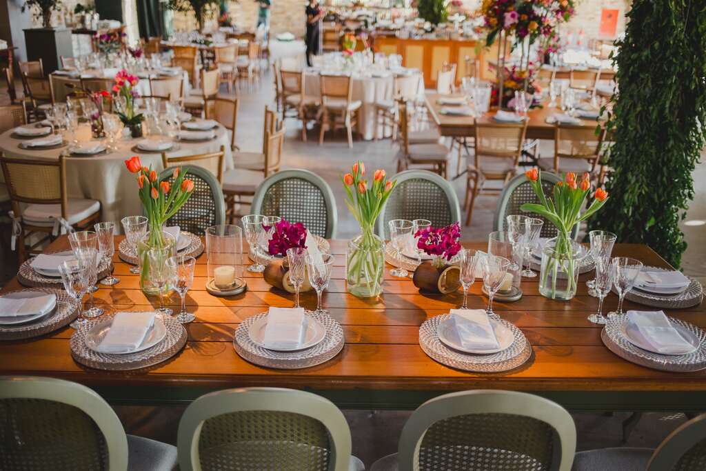 mesa posta com flores rosas e laranjas no centro