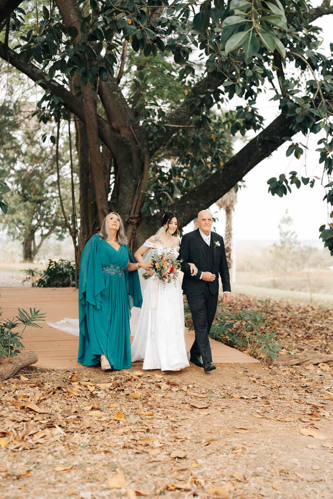 entrada da noiva com a mãe de vestido verde e pai com terno preto