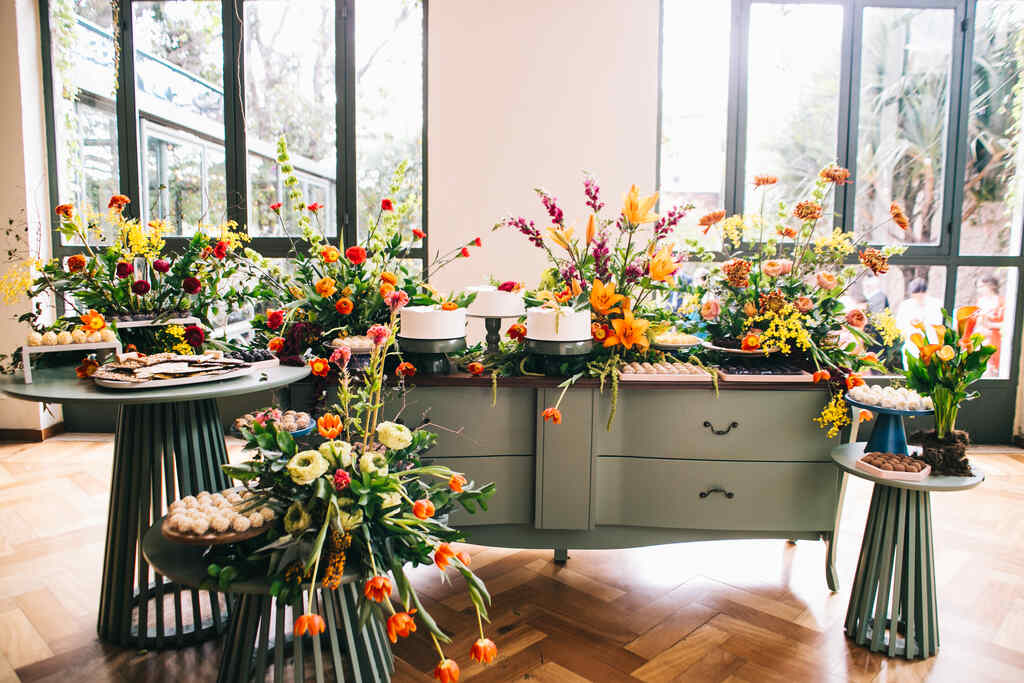 mesa do bolo com flores laranjas vermelhas amarelas e roxas