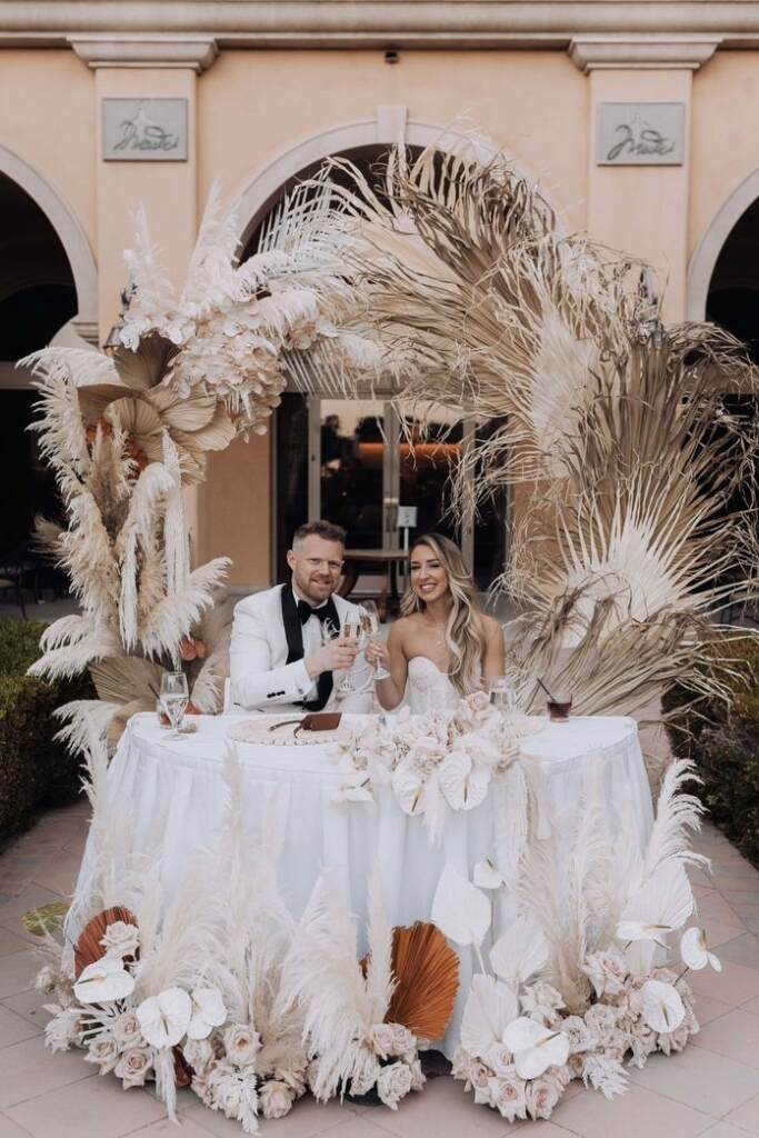 casal sentado em mesa decorada no estilo boho