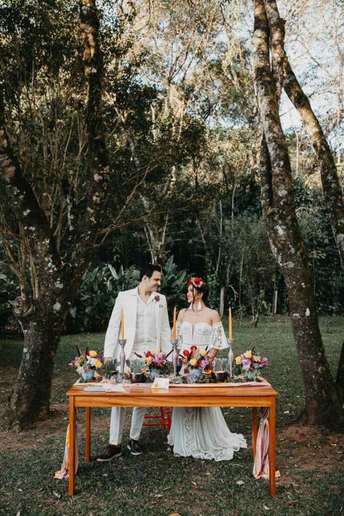 casal de mãos dadas atrás de mesa com flores coloridas