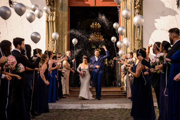 capa post: saída dos noivos na igreja com convidados jogando arroz e outros segurando balões
