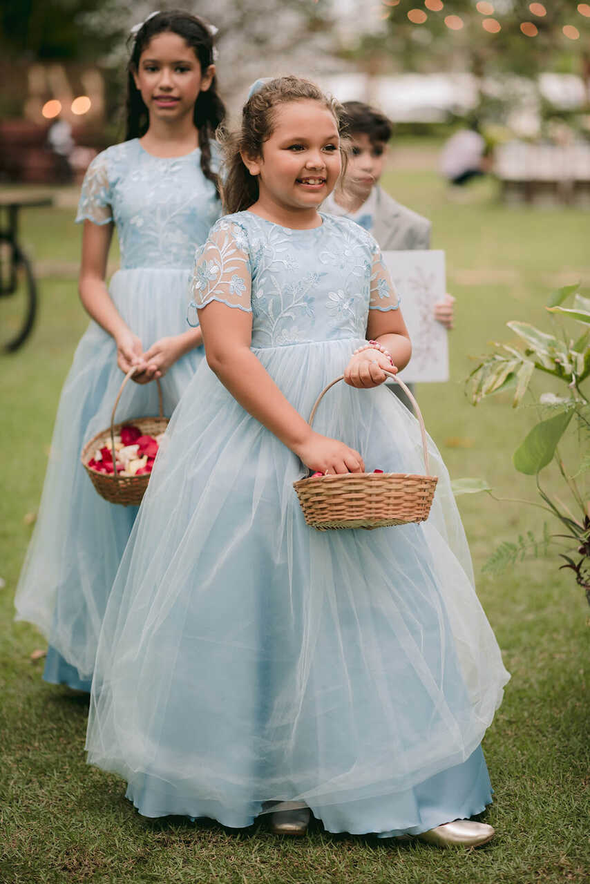 Três meninas floristas, em vestidos azul claro e segurando cestas de flores