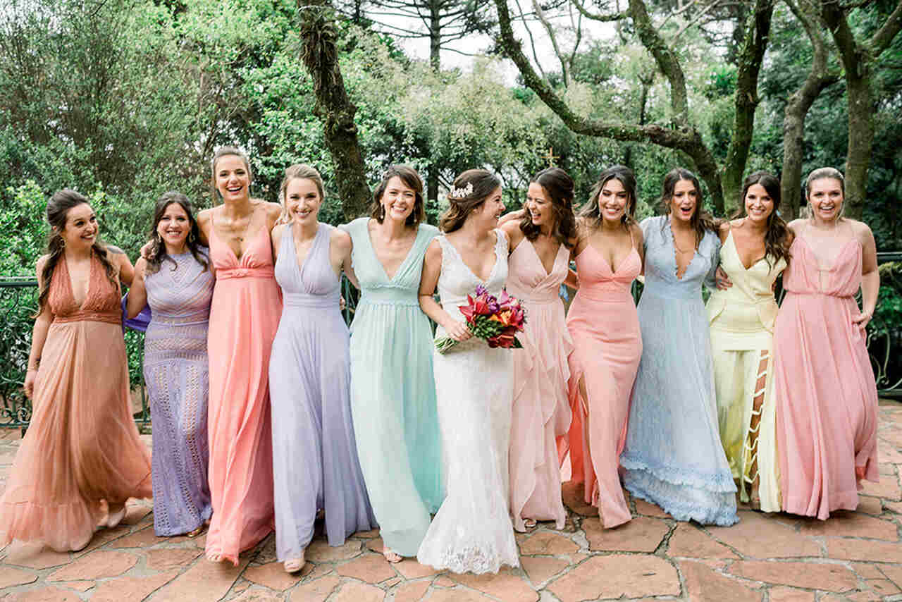 Grupo de madrinhas com vestidos pastel caminhando juntas em um espaço ao ar livre