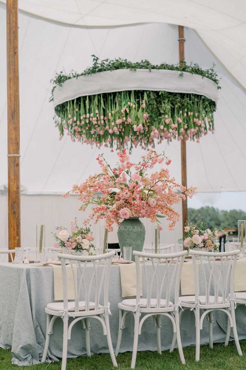 Uma mesa sofisticada com arranjos exuberantes e um lustre suspenso de flores