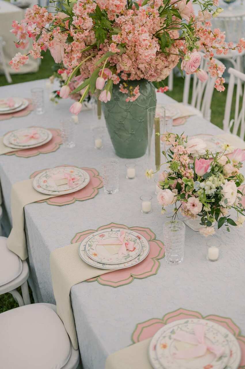 Uma mesa graciosa decorada com flores em tons suaves de rosa, combinando charme floral e elegância nos detalhes refinados.