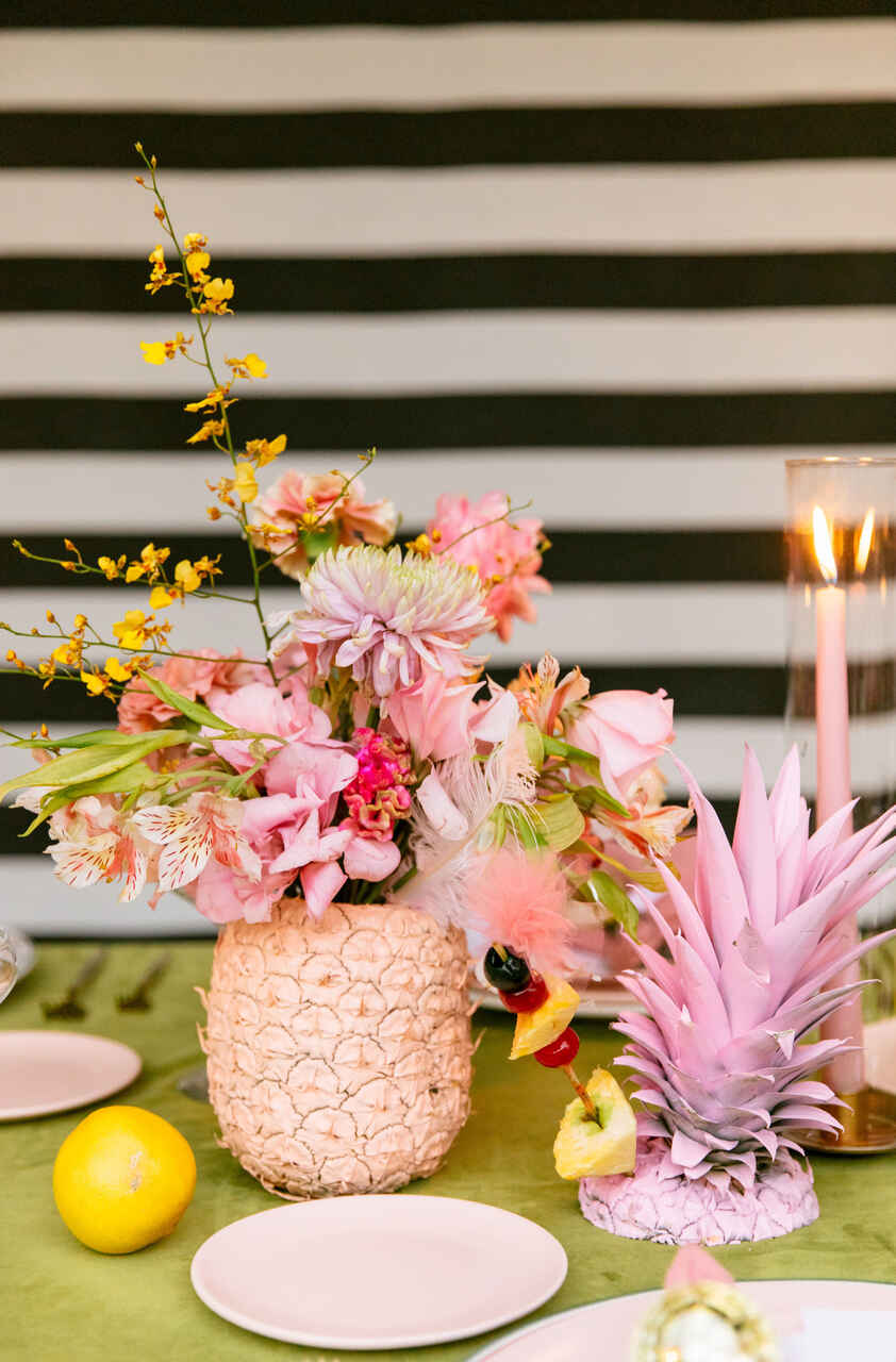 Decoração tropical com flores vibrantes em um abacaxi decorativo, trazendo alegria e leveza à mesa.