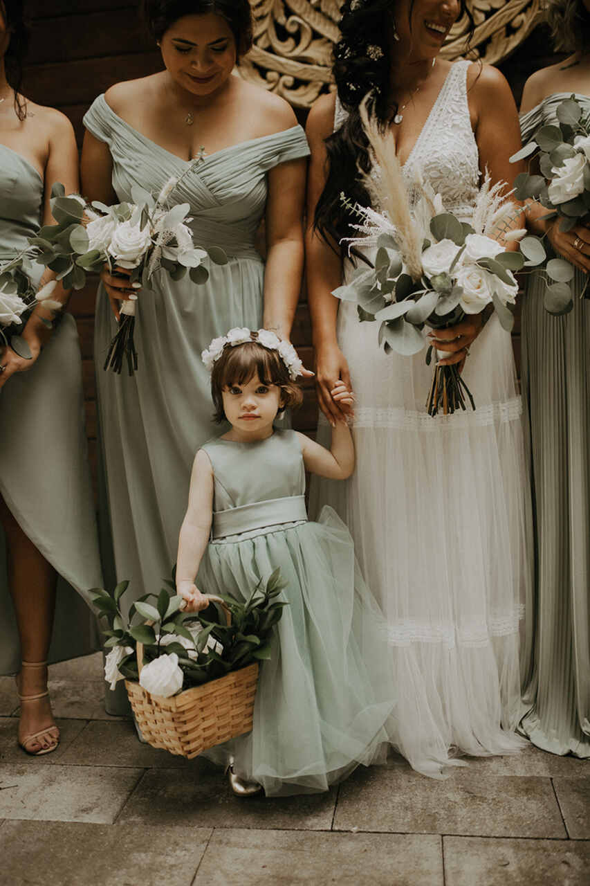 Uma florista usando um vestido verde claro e segurando uma cesta com flores