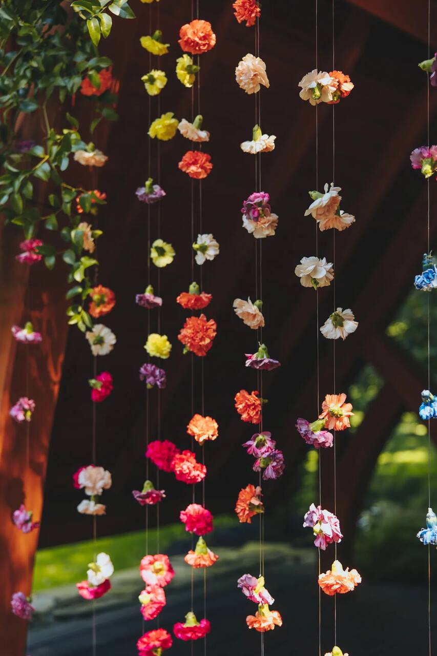 Cortina de flores suspensas multicoloridas, criando um ambiente romântico e delicado ao ar livre