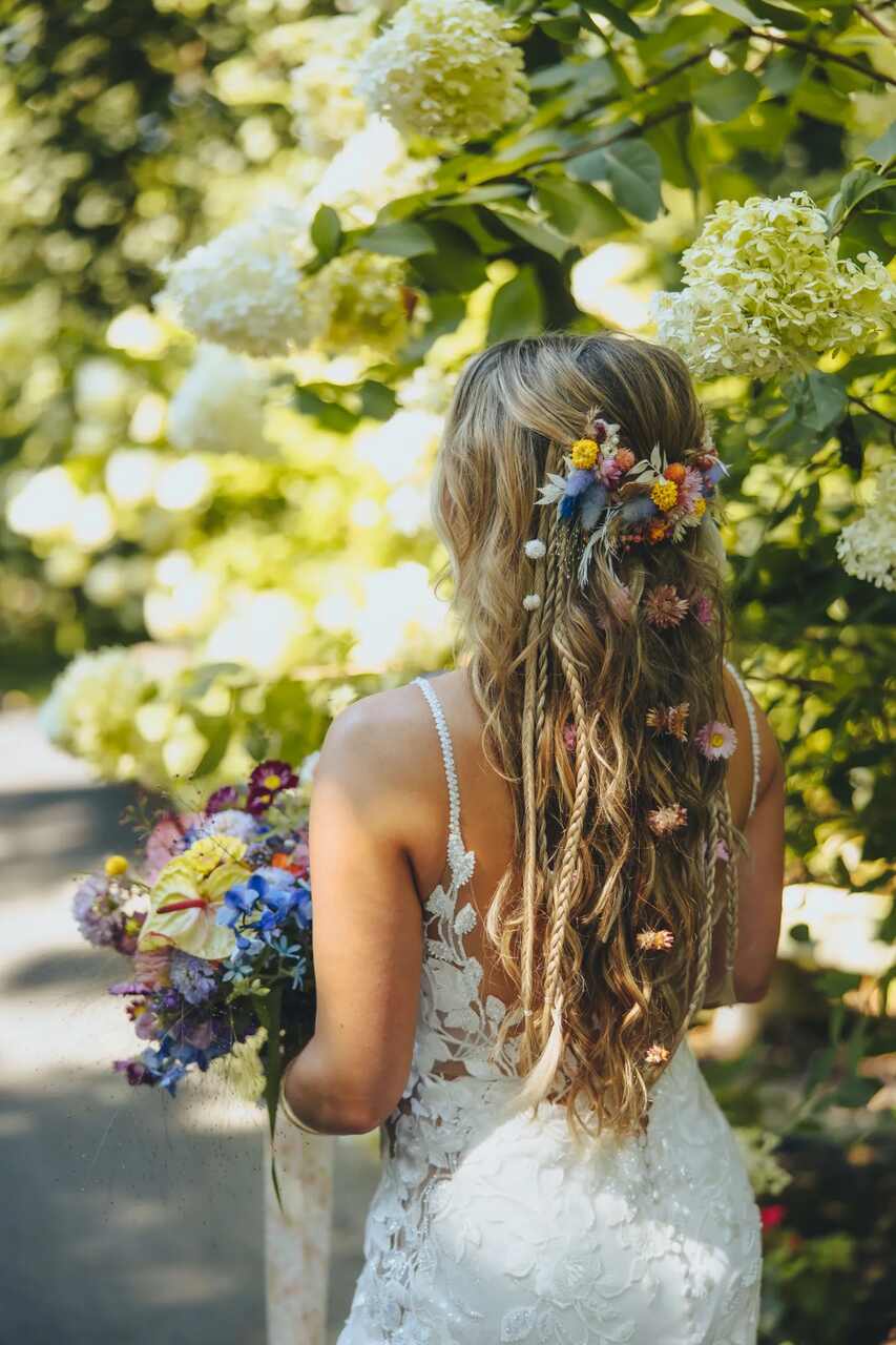 Cabelos longos e soltos adornados com pequenas flores em tons de rosa e amarelo