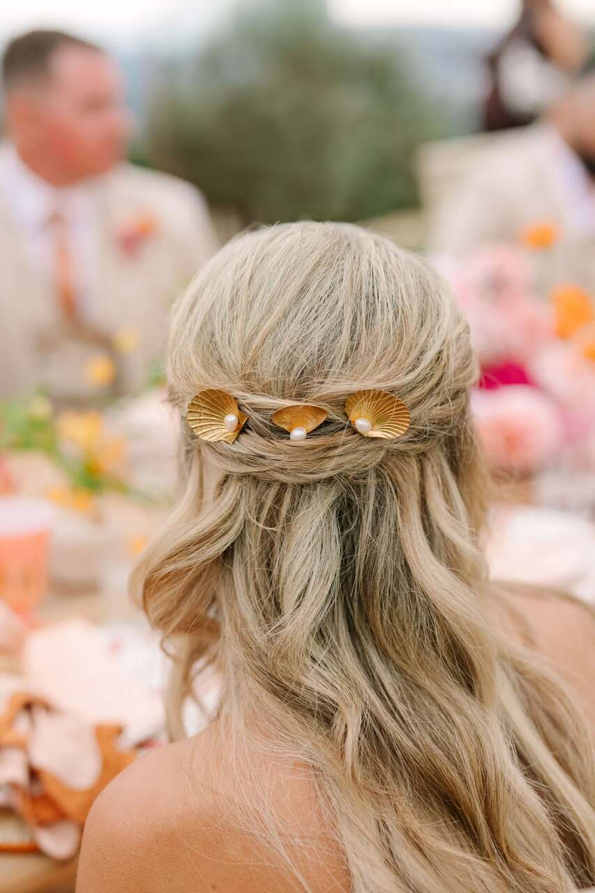 Close de penteado de casamento decorado com presilhas em formato de conchas douradas