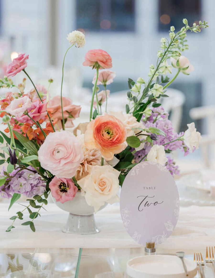 Um arranjo floral em tons pastel marcando a mesa número dois com charme e delicadeza.