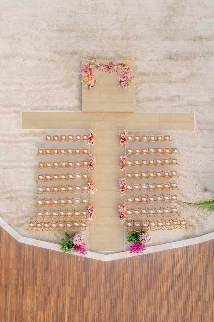 Visão aérea de uma cerimônia de casamento com cadeiras dispostas em formato simétrico e altar decorado com flores