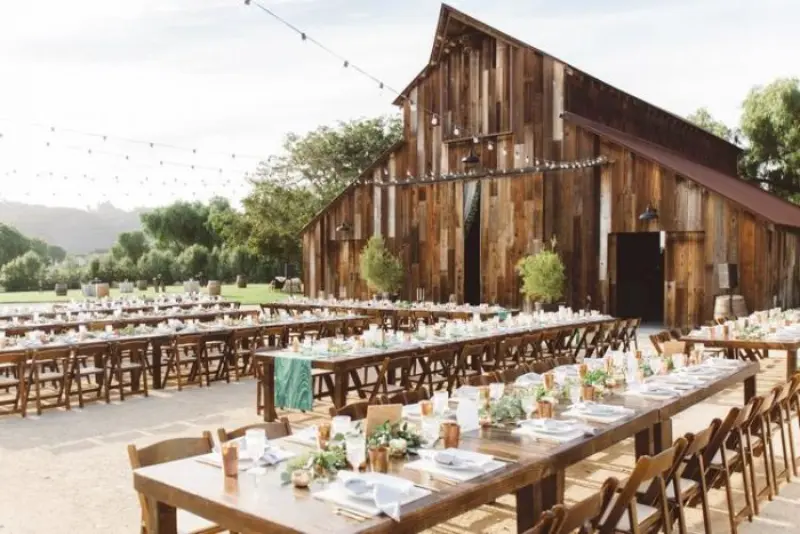 celeiro com mesas comunitárias ao ar livre para casamento rústico no campo