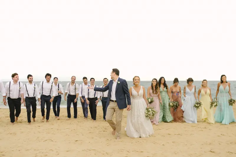 noivos com padrinhos caminhando na praia