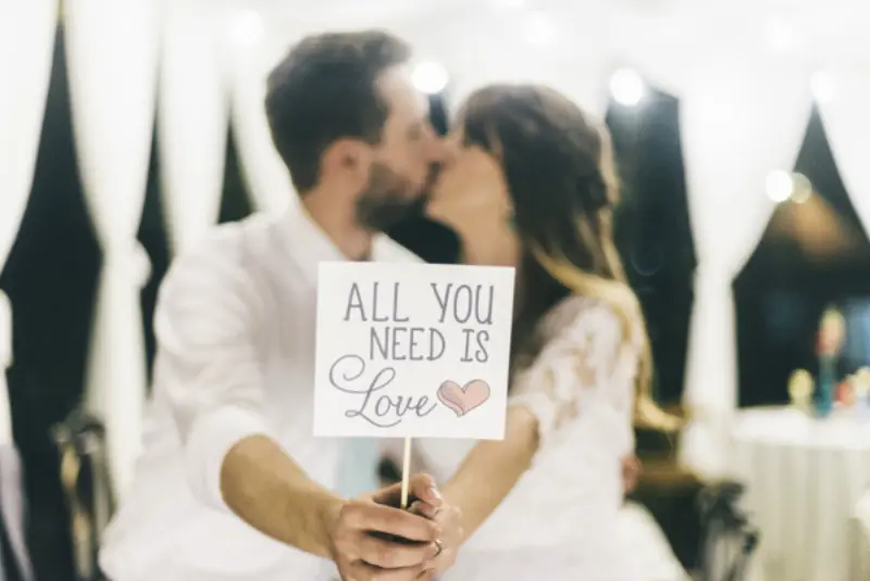 noivos segurando placa com frase All you need is love 