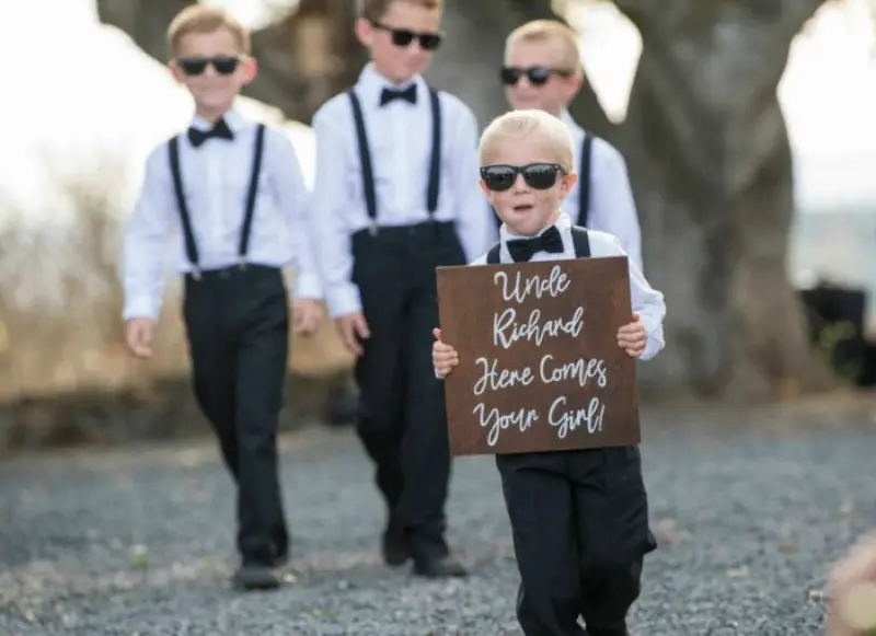 pajem de casamento com plaquinha e óculos escuros
