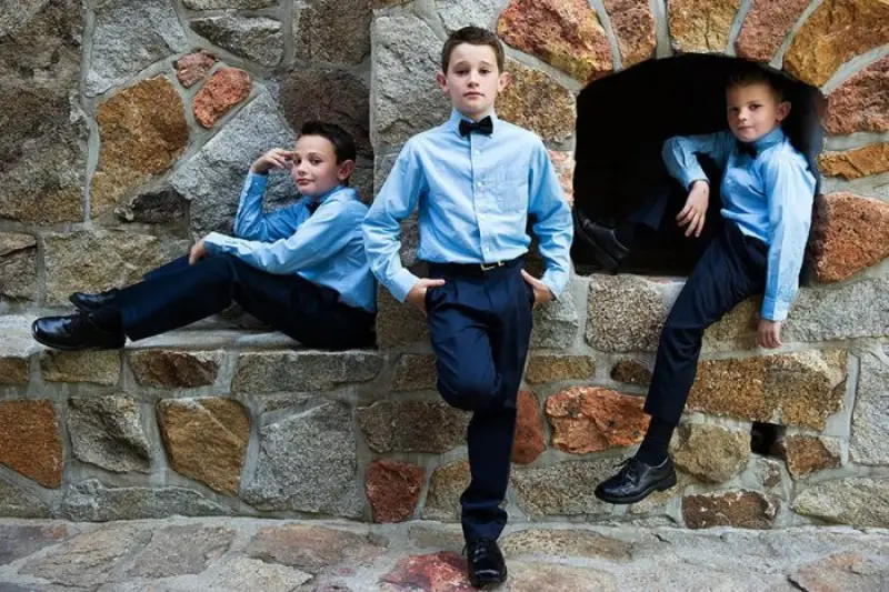 três pajens de casamento posando para foto em muro