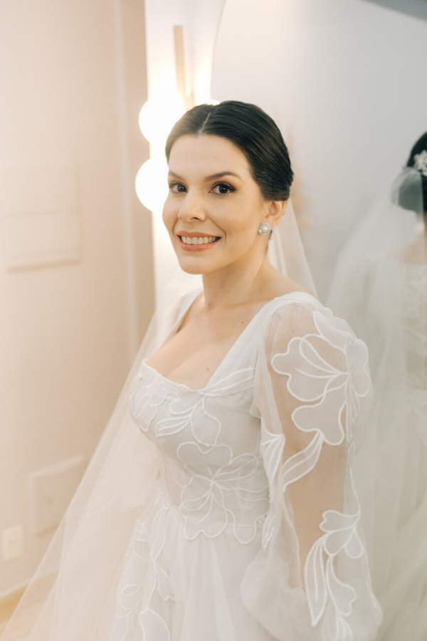 capa post: Noiva sorrindo com vestido de noiva delicado com mangas longas e detalhes florais