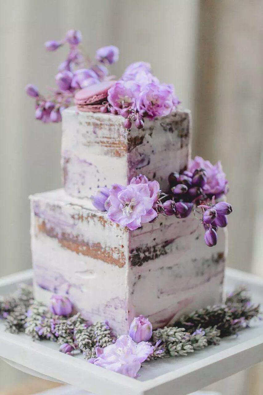 Bolo de dois andares com cobertura rústica e flores naturais no topo.