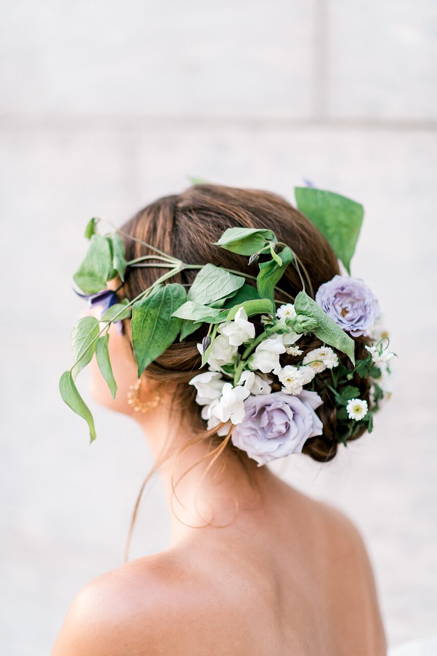 Penteado romântico com flores naturais lilás e folhas verdes