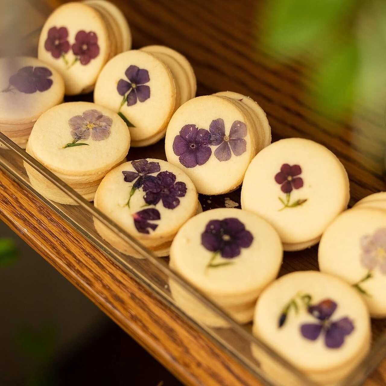 Biscoitos amanteigados delicadamente decorados com flores comestíveis roxas, perfeitos para eventos elegantes