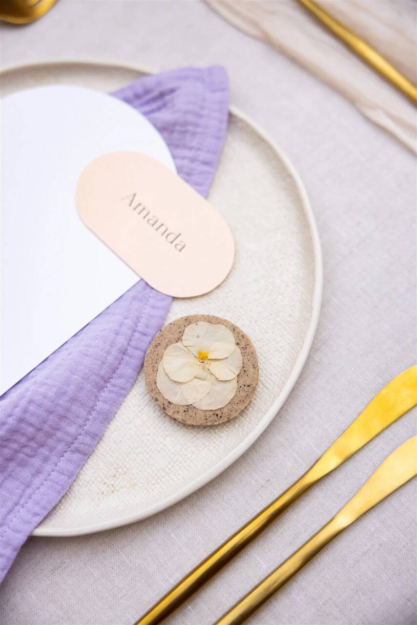 Detalhe de uma mesa de casamento com guardanapo lilás, prato com flores secas e talheres dourados