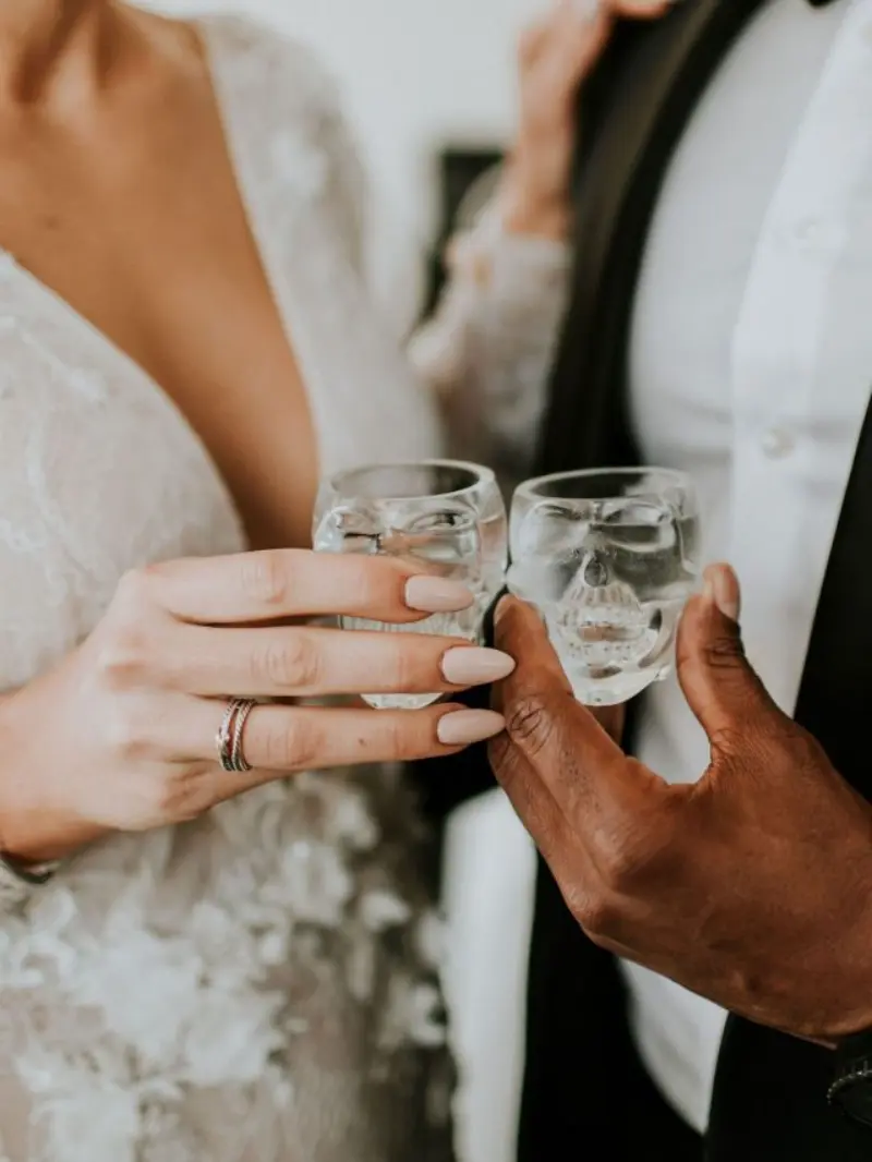casal brindando com copos de shot em formato de caveira