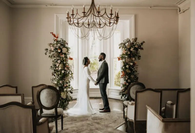 casal em casamento de dia em casa com lustre cl&aacute;ssico e as colunas de flores naturais