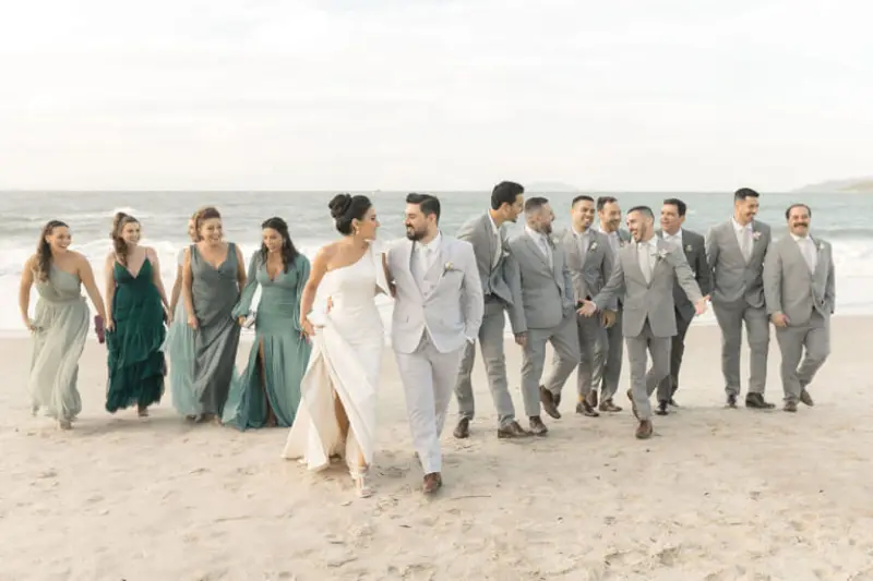noivos e padrinhos caminhando na praia em casamento de dia