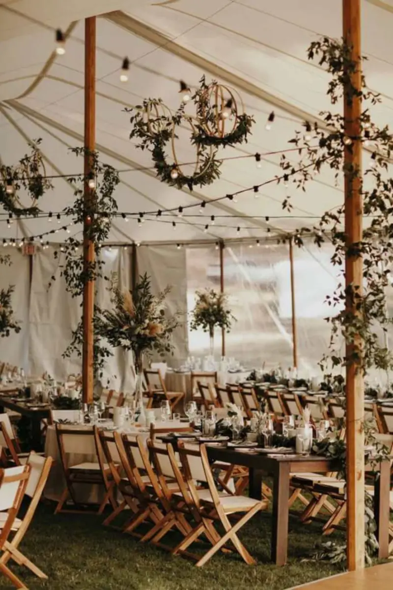 decora&ccedil;&atilde;o de recep&ccedil;&atilde;o de casamento r&uacute;stica com tenda, ilumina&ccedil;&atilde;o de varal de luzes e arranjos bot&acirc;nicos suspensos