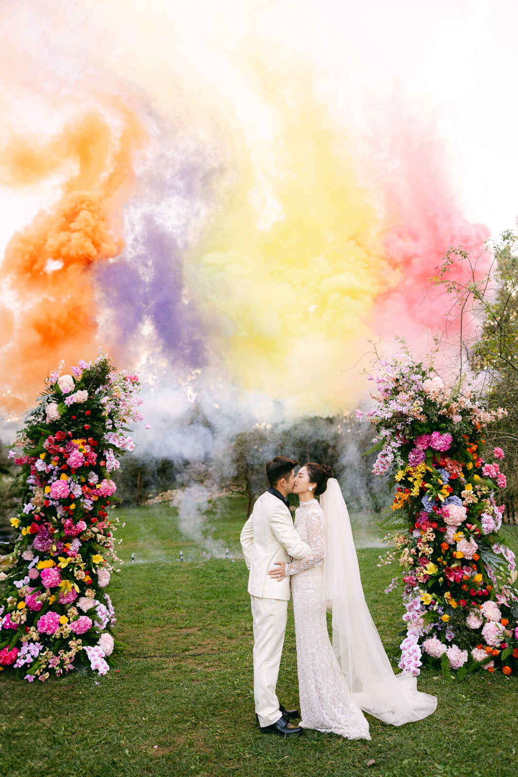 noivos se beijando com fumaça colorida ao fundo