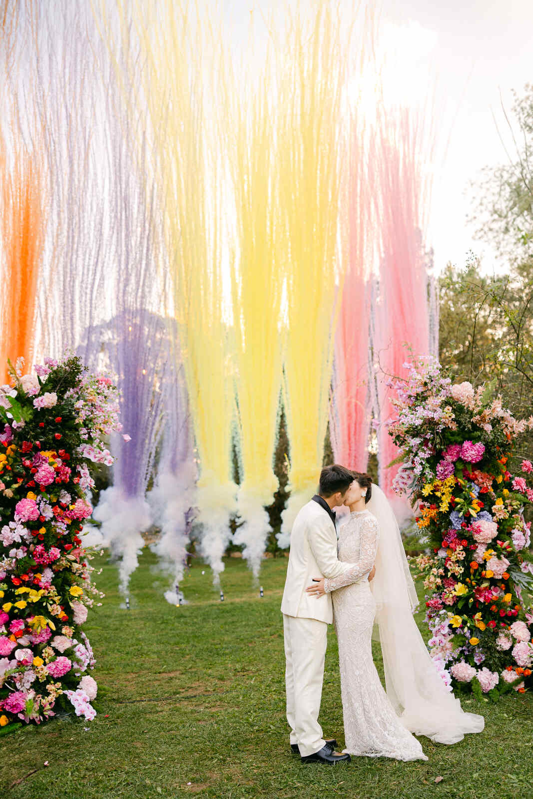 noivos se beijando com fumaça colorida ao fundo