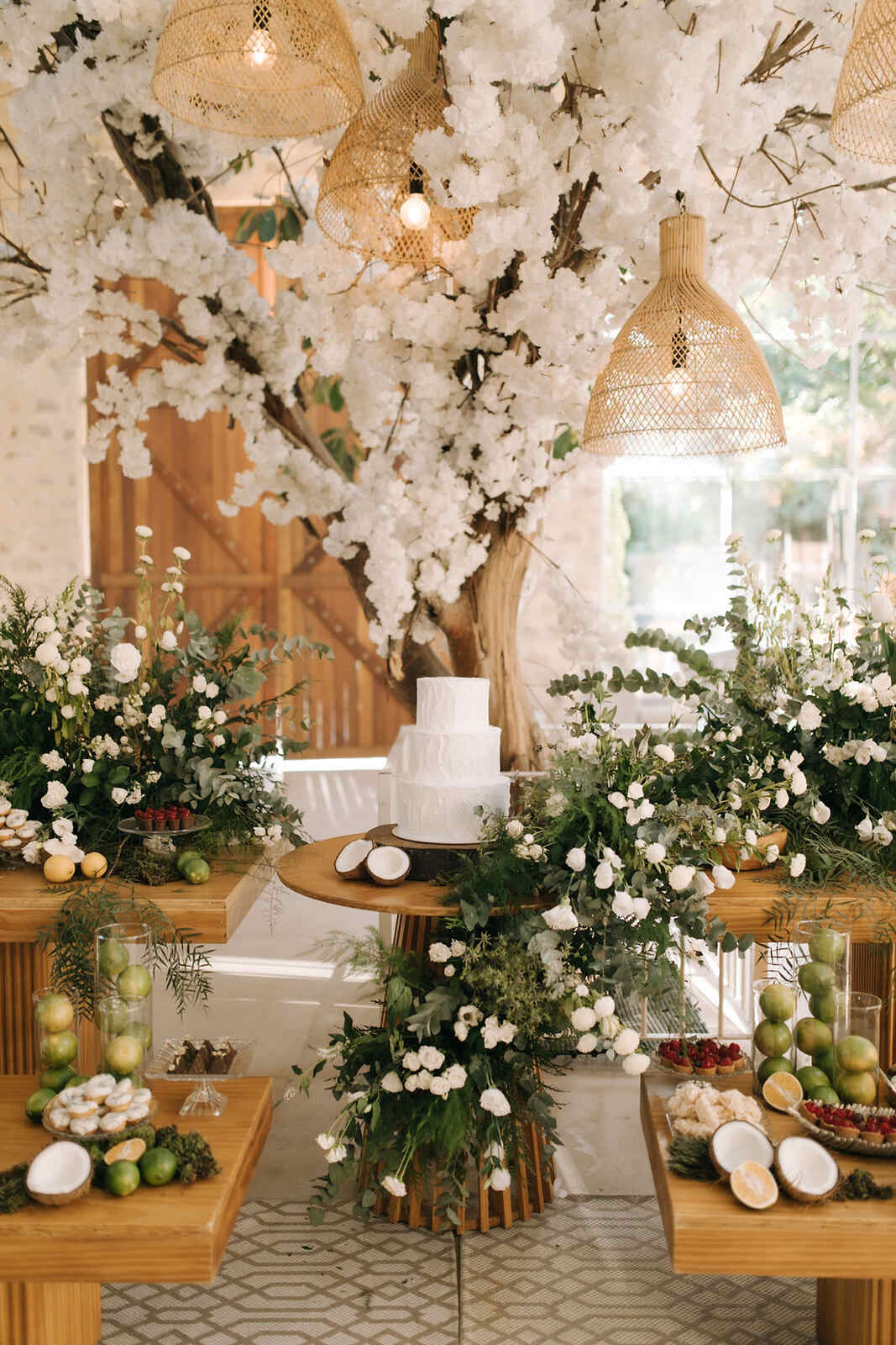 mesa com bolo de casamento e flores brancas