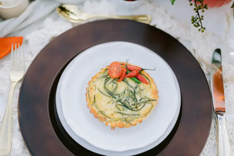 quiche individual, possivelmente recheada com abobrinha ou aspargos