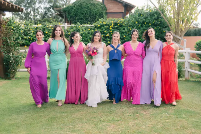 madrinhas com vestidos coloridos em tons vibrantes de rosa, verde, azul e laranja, ao lado da noiva em um vestido de noiva branco