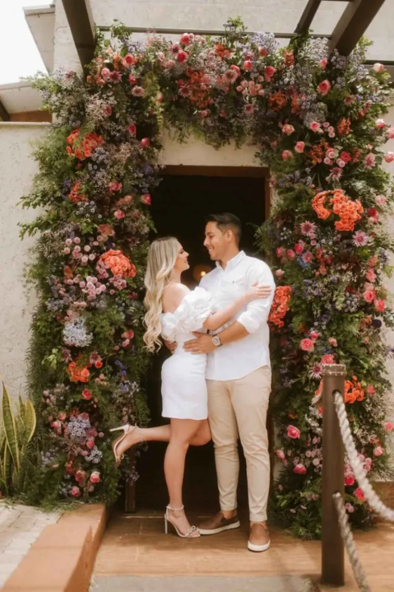 casal em um momento romântico, diante de um grande arco floral