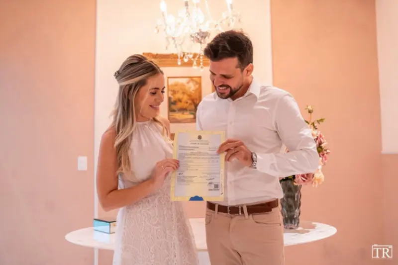 noivos no cart&oacute;rio segurando certid&atilde;o de casamento