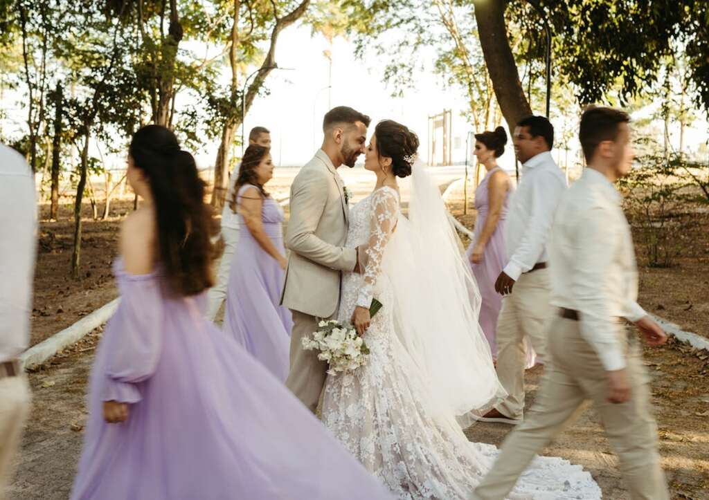 noivos se beijando e padrinhos e madrinhas passando