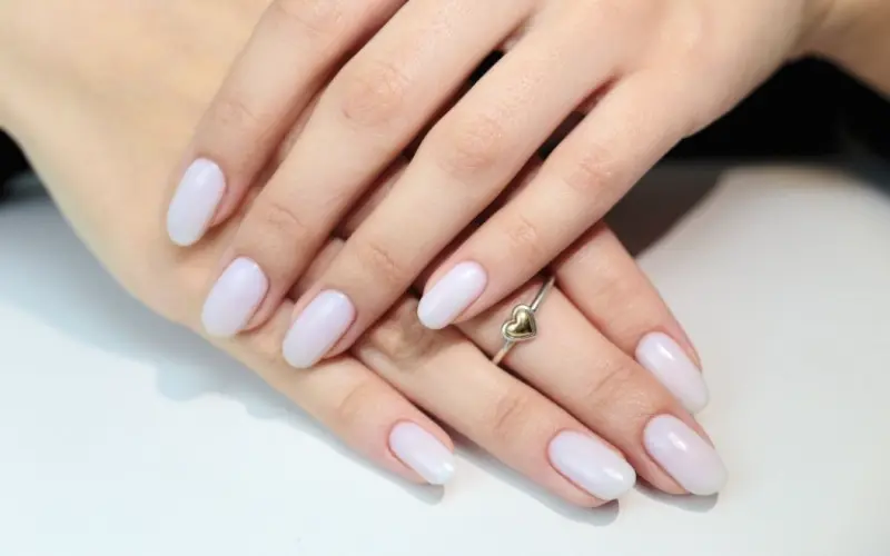 unhas naturais com esmaltação em tom branco leitoso.