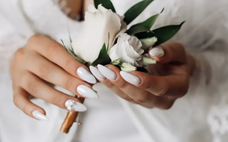 noiva com unhas em formato estileto pintadas de branco com detalhes em pedraria