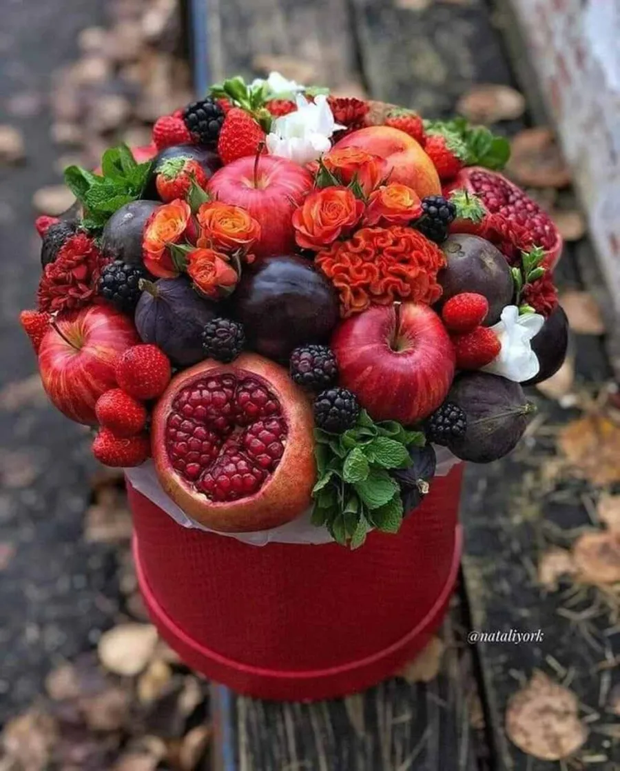 Arranjo de frutas e flores vermelhas dentro de uma caixa de presente