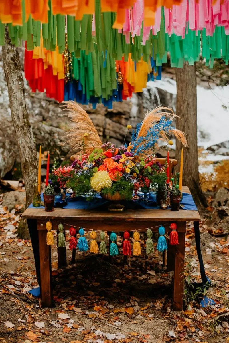 mesa de doces r&uacute;stica apresenta uma paleta de cores vibrantes e celebra&ccedil;&otilde;es folcl&oacute;ricas com fitas suspensas