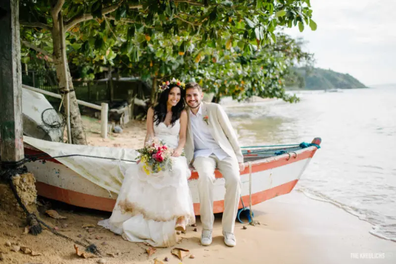 casal sentado na canoa a beira da praia em casamento tropical
