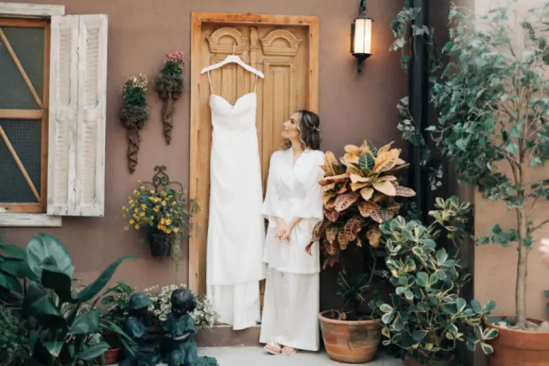 noiva olhando para vestido pendurado na porta