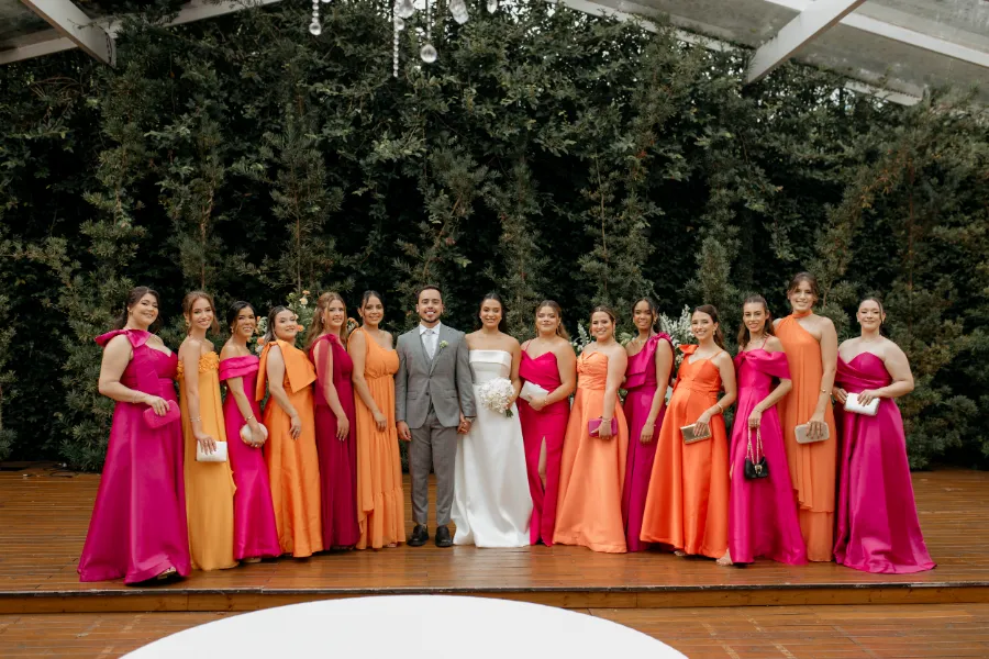 noivos ao lado de madrinhas de vestido rosa e laranja